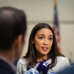 Woman speaking to journalists with microphones nearby