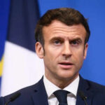 Man speaking at podium in front of flags