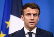 Online Free Speech: Macron’s Explosive Critique Man speaking at podium in front of flags