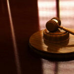 Trump Attorney Now Running DOJ—Prosecutors Walk Out Gavel on a wooden table in sunlight