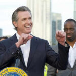 Person speaking at podium with others in background