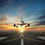 Airplane landing on runway during sunset sky