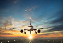 Airplane landing on runway during sunset sky
