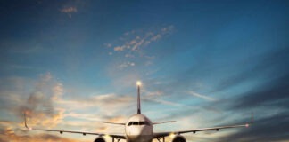 Airplane landing on runway during sunset sky