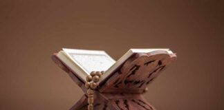 A beautifully crafted wooden stand holding an open Quran with prayer beads