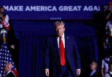 Trump’s State of the Union Sparks GOP Chaos Person in red tie at rally under blue banner