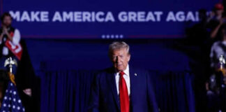 Person in red tie at rally under blue banner