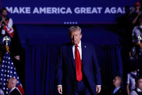 Person in red tie at rally under blue banner