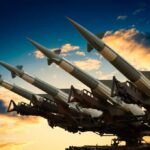 Cruise missile launcher with missiles pointed upwards against a sunset sky