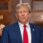 I dont know who this is. Man speaking, indoors, wearing suit.