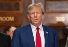 I dont know who this is. Man speaking, indoors, wearing suit.