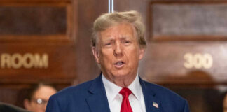 I dont know who this is. Man speaking, indoors, wearing suit.