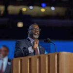 Man speaking at podium on stage with microphone