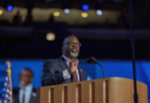 Man speaking at podium on stage with microphone