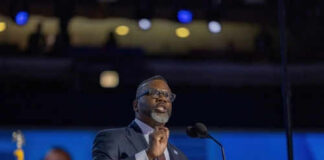 Man speaking at podium on stage with microphone