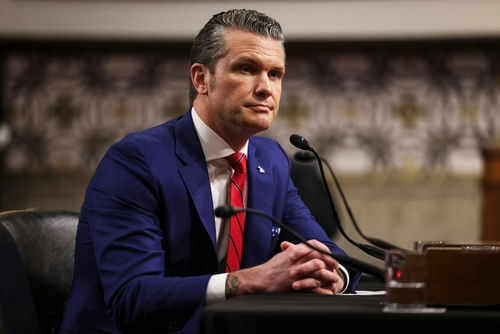 pete-hegseth2586168539 Man in suit sitting at a desk with microphone