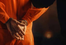 Person in orange jumpsuit with hands cuffed behind