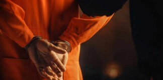 Person in orange jumpsuit with hands cuffed behind