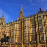 The Houses of Parliament in London with a statue in the foreground