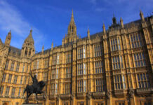 The Houses of Parliament in London with a statue in the foreground