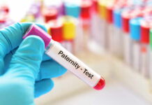 Hand holding a blood sample labeled for a paternity test