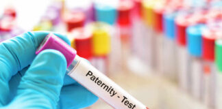 Hand holding a blood sample labeled for a paternity test