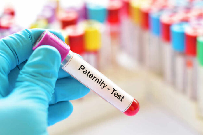 Hand holding a blood sample labeled for a paternity test