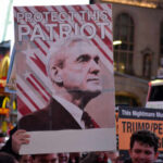 Crowd holding a sign that reads 'Protect This Patriot' with an image of a man