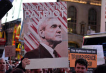 Crowd holding a sign that reads 'Protect This Patriot' with an image of a man