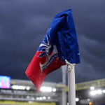 Corner flag of Crystal Palace F.C. at a stadium under dark clouds