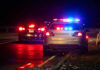 Police car with flashing lights parked on the roadside at night
