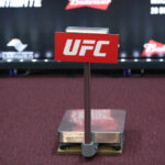 UFC weighing scale with promotional signage in the background