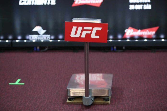 UFC weighing scale with promotional signage in the background