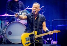 A musician passionately performing on stage with a guitar