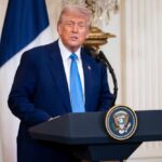 Donald Trump delivering a speech at a podium in the White House