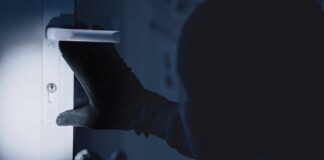 A gloved hand attempting to unlock a door in low light