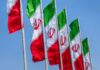 Multiple Iranian flags waving against a clear blue sky
