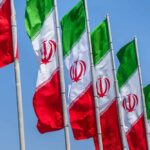 Multiple Iranian flags waving against a clear blue sky