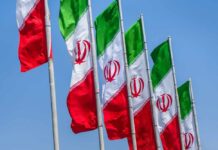 Multiple Iranian flags waving against a clear blue sky
