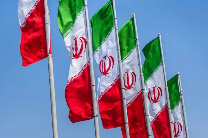 Multiple Iranian flags waving against a clear blue sky