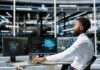 A man working at a computer workstation with multiple screens displaying data visualizations