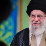 A religious leader speaking in traditional attire against a colorful background