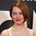 A woman with short red hair smiling at a red carpet event