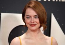 A woman with short red hair smiling at a red carpet event