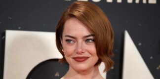 A woman with short red hair smiling at a red carpet event