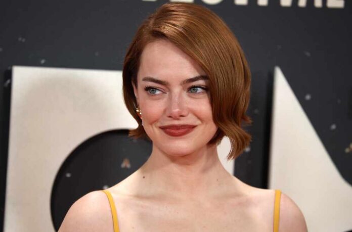 A woman with short red hair smiling at a red carpet event