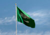 Saudi Arabian flag waving against a blue sky