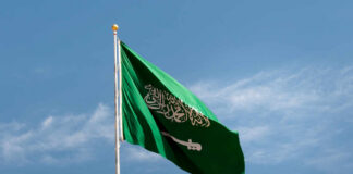 Saudi Arabian flag waving against a blue sky