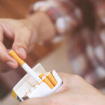 Hand holding cigarette and pack close up