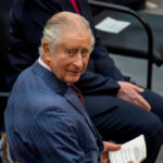Man in suit holding paper seated and smiling